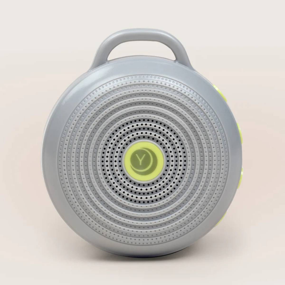 A round, gray portable speaker with circular perforations and a yellow power button, featuring a handle for easy transport. 