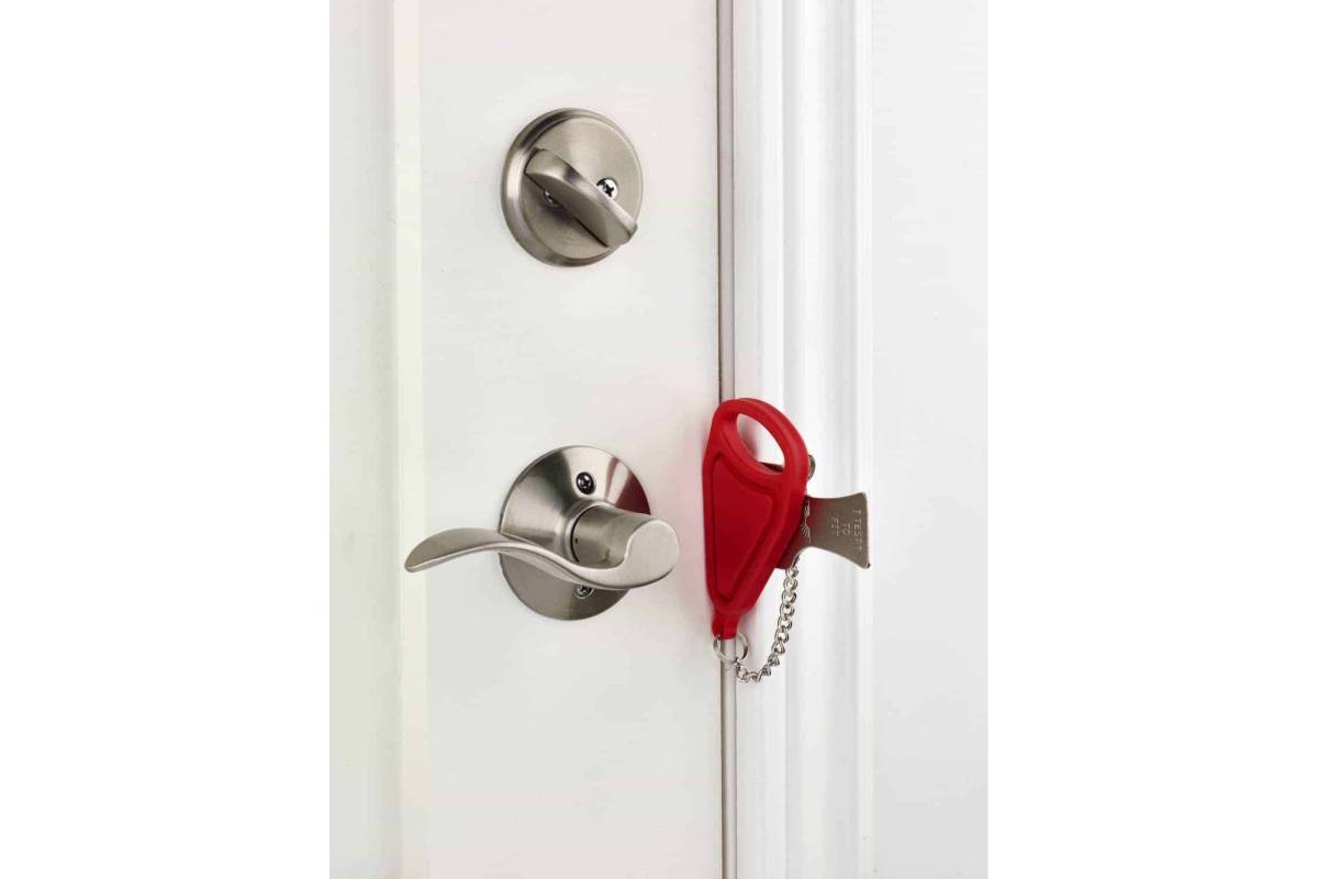 Close-up of a door handle and lock with a red safety key attached, set against a white door. 