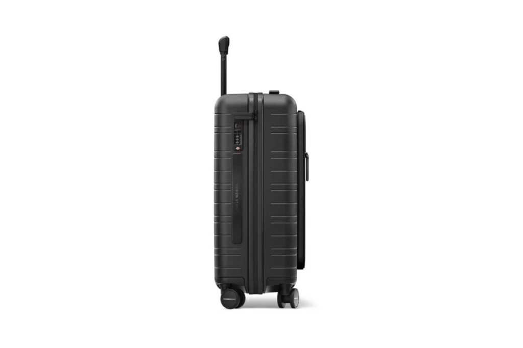 A sleek black hard-shell suitcase with a retractable handle and wheels, featuring a lock and grooves for style and durability.